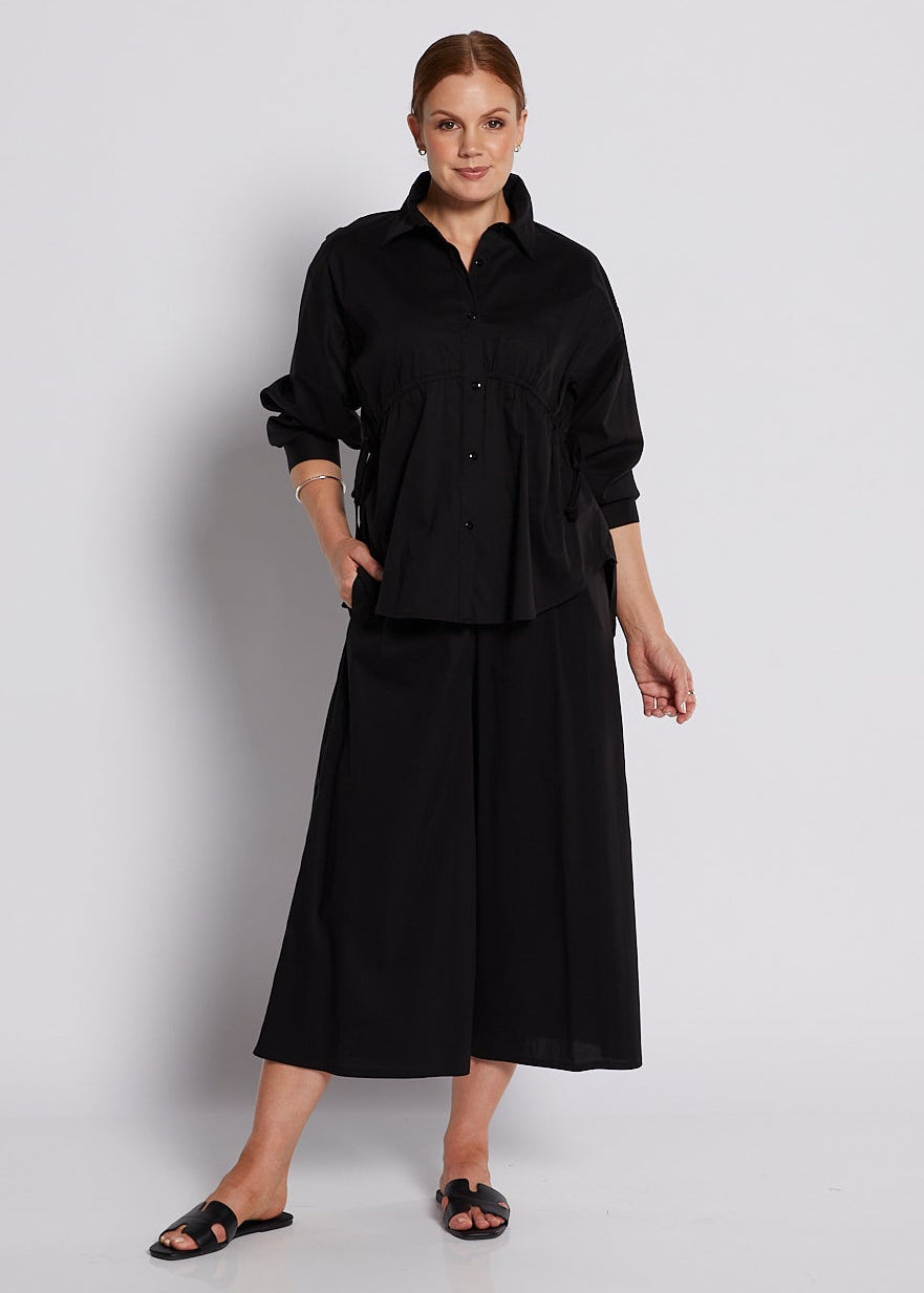Person wearing a black outfit against a white background