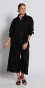 Person wearing a black outfit standing against a white background