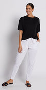 Person wearing a black t-shirt and white pants against a white background