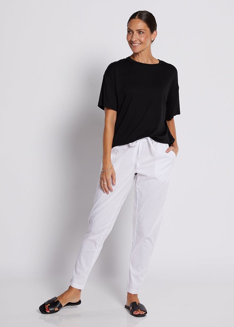 Person wearing a black t-shirt and white pants against a white background