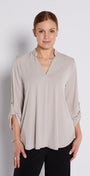 Woman wearing a beige blouse against a plain background