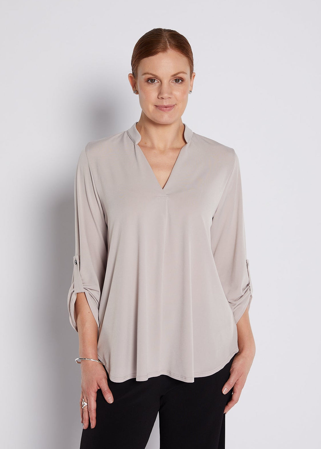 Woman wearing a beige blouse against a plain background