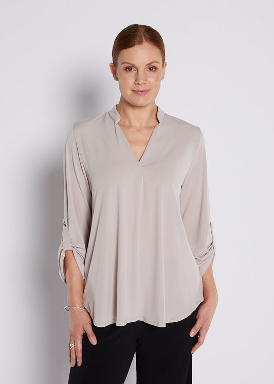 Woman wearing a beige blouse against a plain background