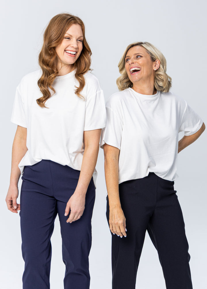 Woman wearing a white top and black pants on a white background