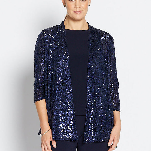 Woman wearing a navy sequin jacket, navy top, and wide-leg pants on a white background