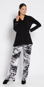 Woman wearing a black top and patterned pants on a white background