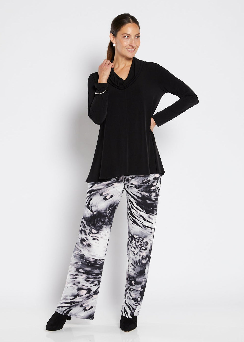 Woman wearing a black top and patterned pants on a white background