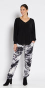 Woman wearing a black top and patterned pants on a white background