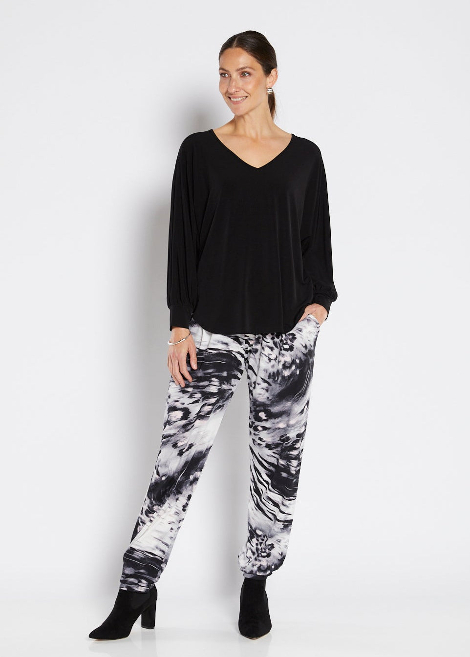 Woman wearing a black top and patterned pants on a white background