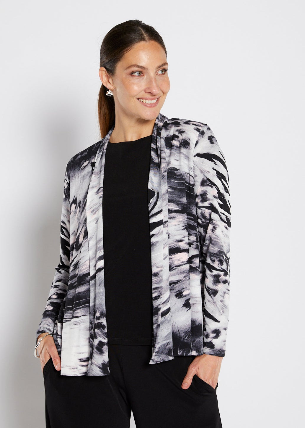 Woman wearing a patterned jacket over a black top on a white background
