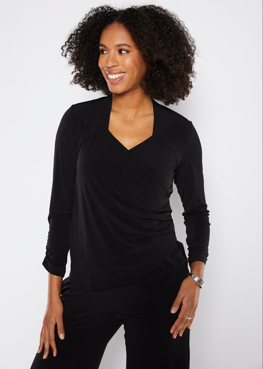 Woman wearing a black long-sleeve top against a white background