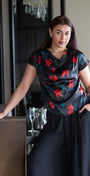 Woman in a floral dress standing in a room with chairs and decor.