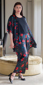 Woman in a floral outfit standing in a room with a mirror and ottoman.