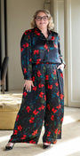 Woman wearing a patterned outfit standing in a room with a mirror and furniture.