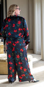 Woman wearing a floral outfit in a room with a mirror and furniture.