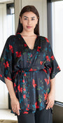 Woman wearing a floral kimono-style top in a room with a mirror.