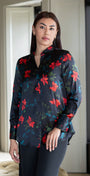 Woman wearing a black floral blouse standing in a room with neutral decor.