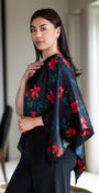 Woman wearing a floral shawl in a room with a table and chair.
