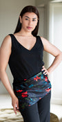Woman wearing a black sleeveless top and colorful skirt in an indoor setting