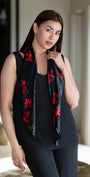 Woman wearing a black sleeveless top with a floral scarf in a room.