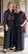 Two women in matching outfits standing in a room with neutral decor.