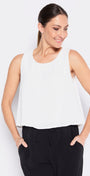 Woman wearing a white sleeveless top and black pants on a white background