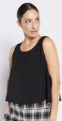 Woman wearing a black sleeveless top and plaid pants against a white background