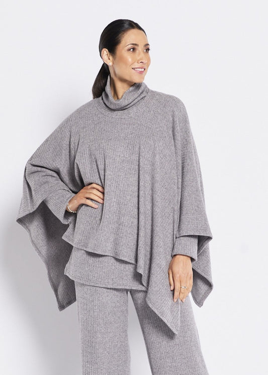 Woman wearing a gray outfit with a poncho-style top and wide-leg pants on a white background