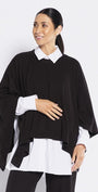 Woman wearing a black poncho over a white shirt and black pants on a white background