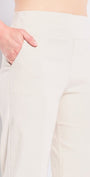 Person wearing white pants and black shoes on a plain background