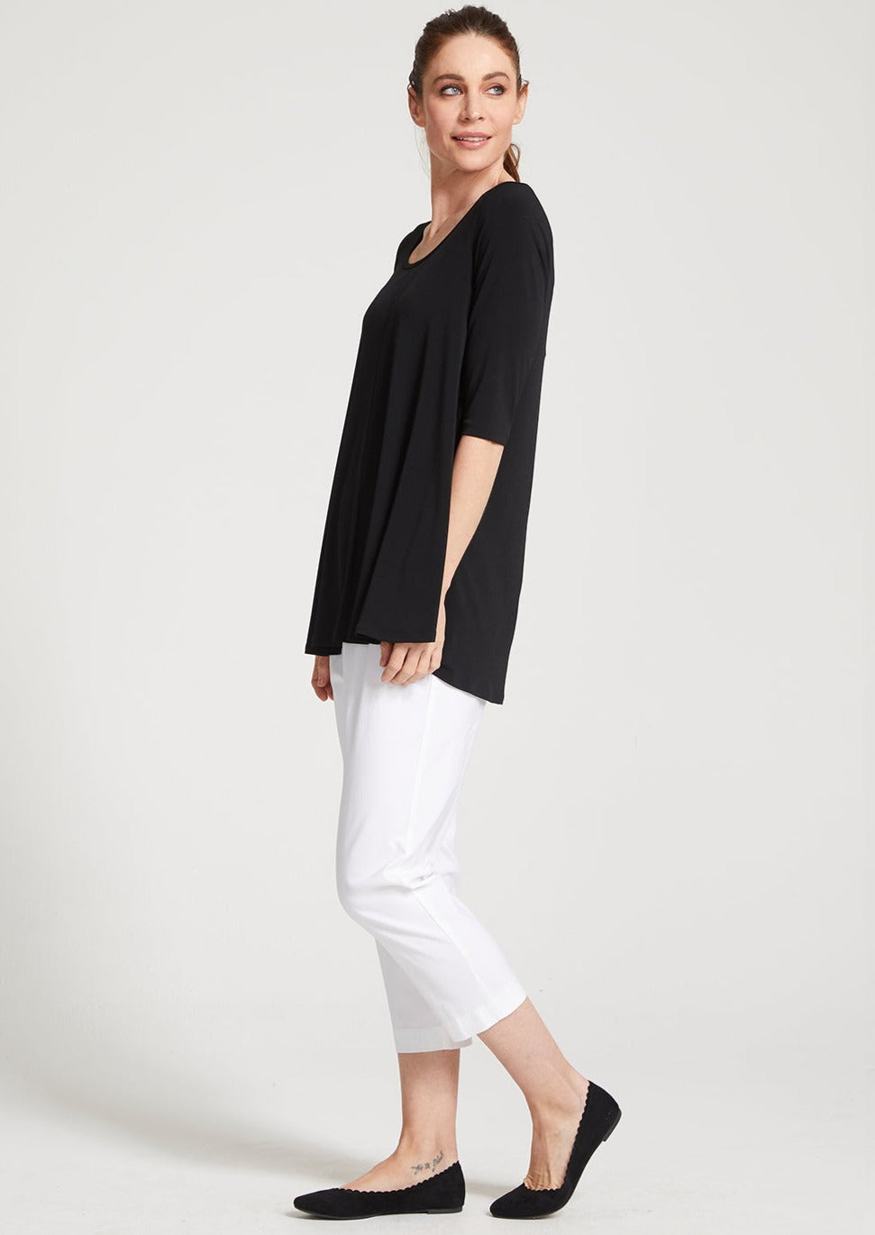Adora is a Spring Summer 3/4 cropped white pant. Cut at calf length, with an easy comfortable pull on elastic waist and slim legs. Image is front side angle view of model. Philosophy Australia bengaline 3/4 length pant.