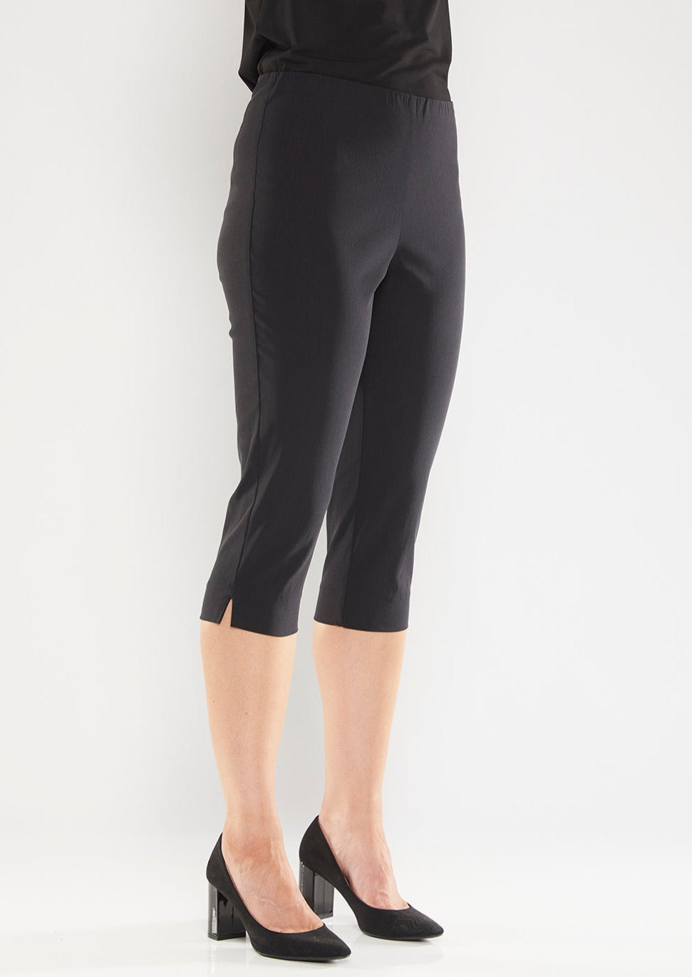 The black Capri feature a below the knee-length pull on style, elasticated waist and slim cut leg. Image is model is standing at a front angle. Philosophy Australia bengaline knee length pant.
